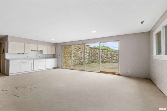 unfurnished living room with brick wall