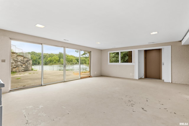 unfurnished living room featuring brick wall