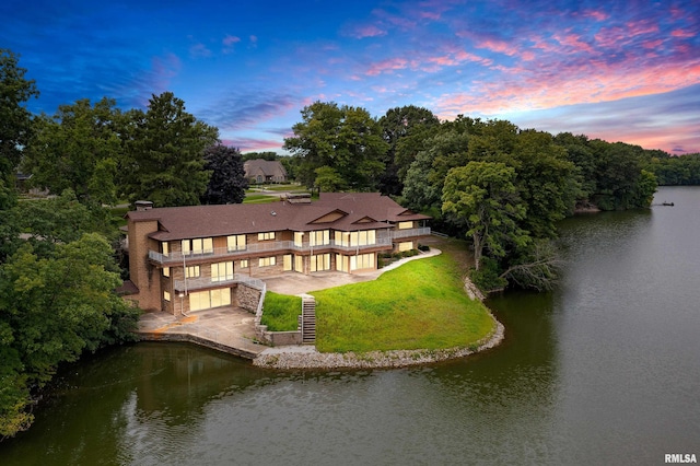 aerial view at dusk featuring a water view