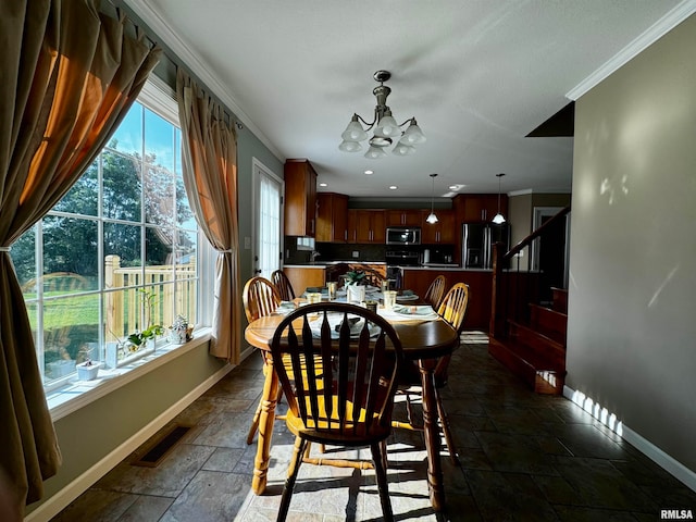 dining space with crown molding, sink, and a notable chandelier