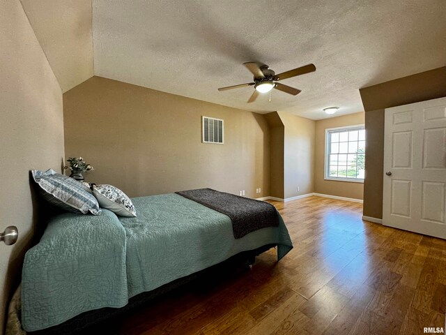 bedroom featuring lofted ceiling, ceiling fan, wood-type flooring, and a textured ceiling