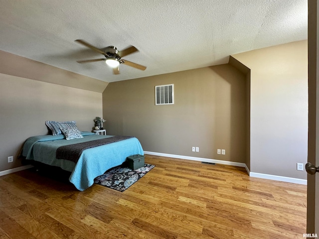 bedroom with hardwood / wood-style floors, a textured ceiling, and ceiling fan