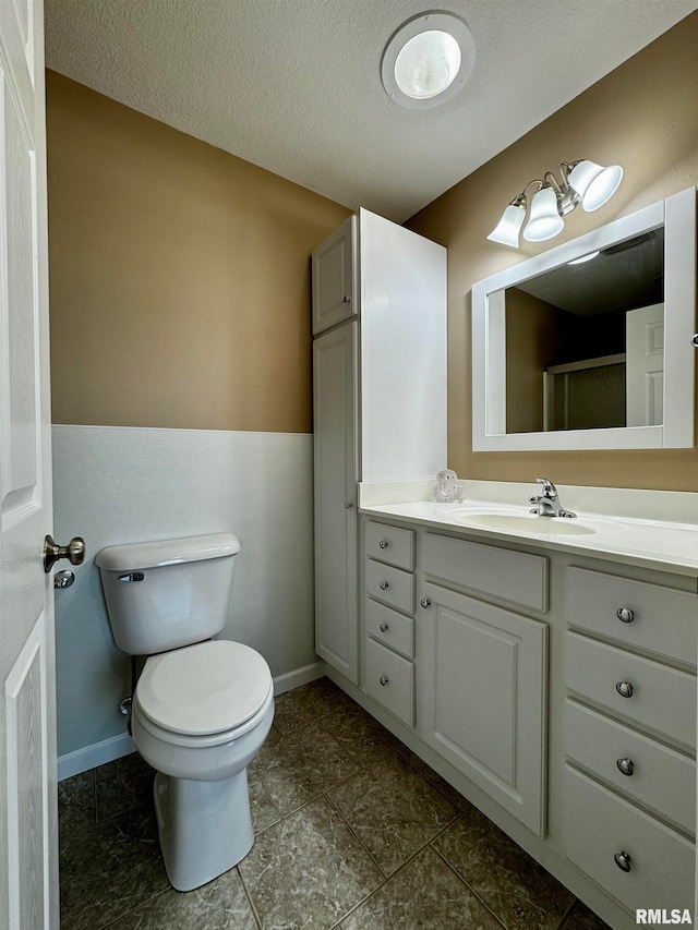 bathroom featuring walk in shower, vanity, toilet, and a textured ceiling