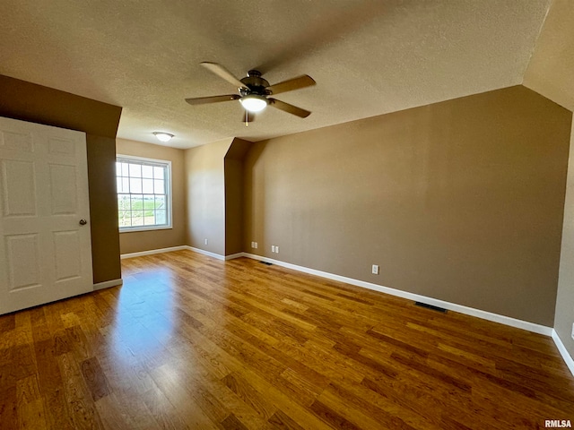 interior space featuring lofted ceiling, a textured ceiling, hardwood / wood-style flooring, and ceiling fan