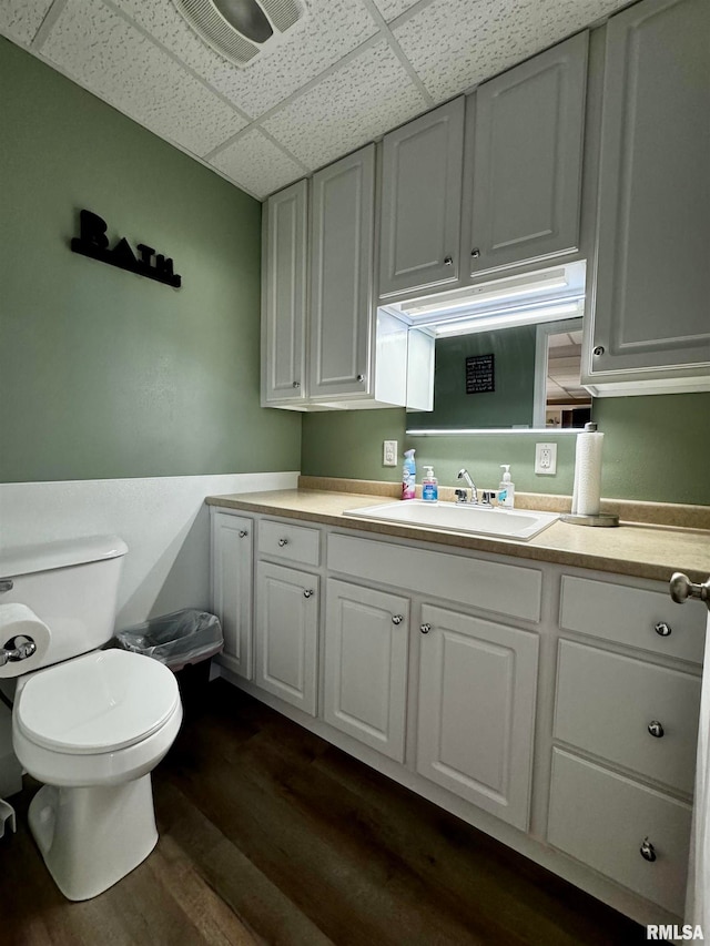 bathroom with vanity, wood-type flooring, toilet, and a paneled ceiling