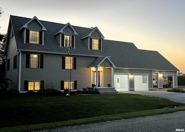 new england style home featuring a garage and a lawn