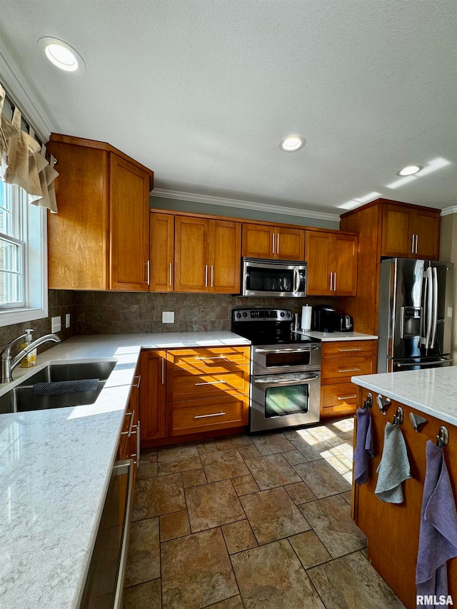 kitchen featuring tasteful backsplash, light stone countertops, sink, stainless steel appliances, and ornamental molding