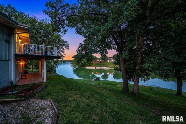 yard at dusk with a balcony and a water view