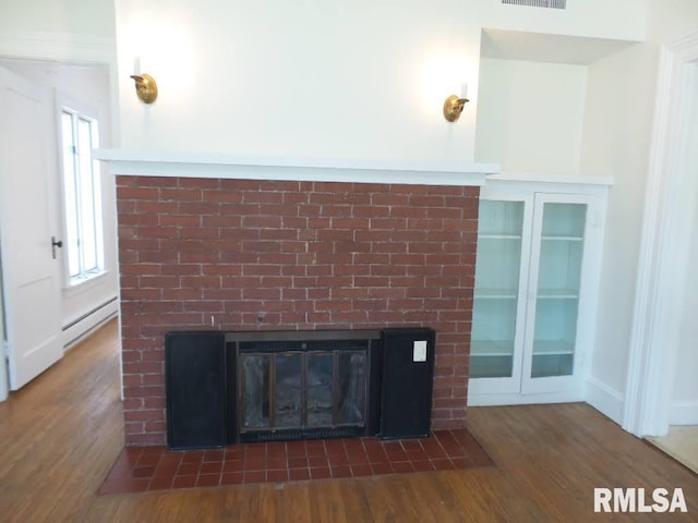 interior details featuring a fireplace, wood-type flooring, and a baseboard heating unit