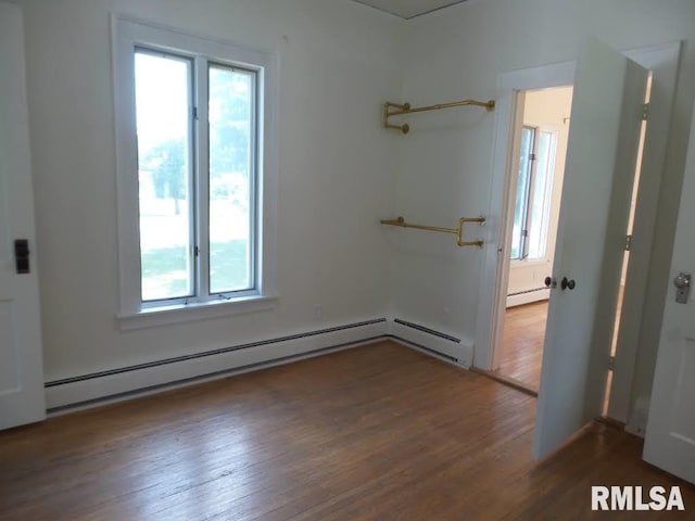 empty room featuring dark hardwood / wood-style floors and a baseboard radiator