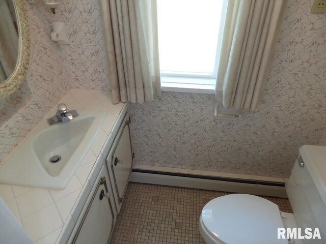 bathroom with toilet, vanity, and a baseboard heating unit