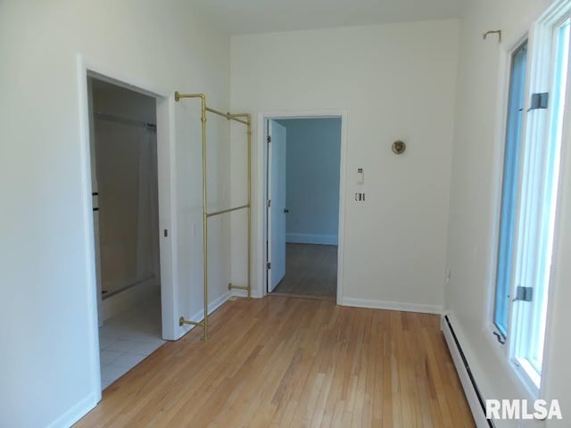 unfurnished room with light hardwood / wood-style flooring and a baseboard heating unit