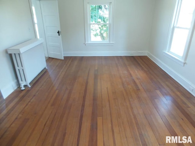 unfurnished room featuring radiator and dark wood-type flooring