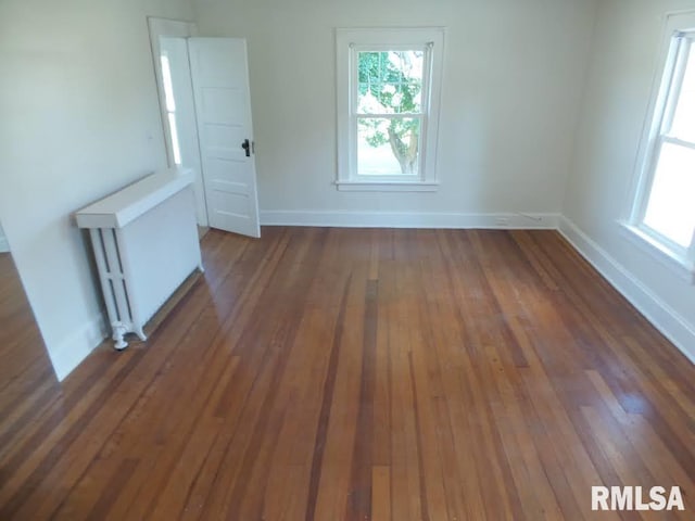 spare room featuring radiator and dark wood-type flooring