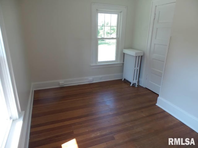 empty room with radiator heating unit and dark wood-type flooring