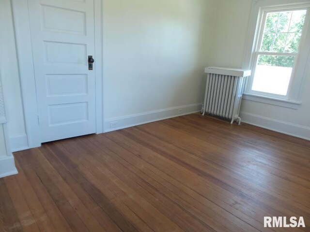 spare room featuring radiator heating unit and dark hardwood / wood-style flooring