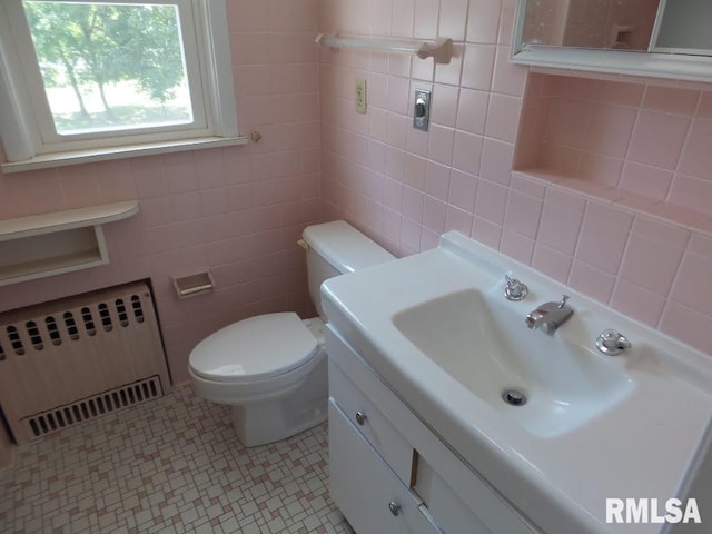 bathroom with radiator heating unit, vanity, tile walls, and toilet