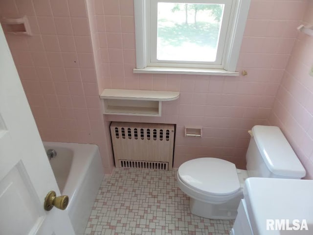 bathroom featuring a bathtub, toilet, radiator heating unit, and tile walls