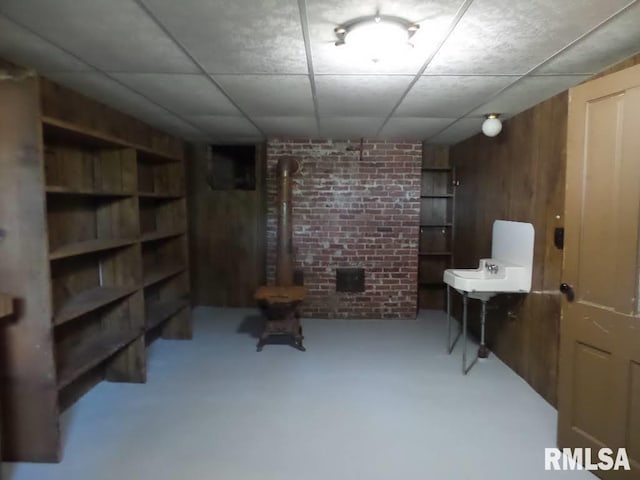 basement featuring wood walls and a drop ceiling