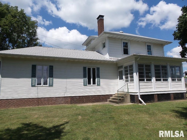 rear view of house with a lawn and a sunroom