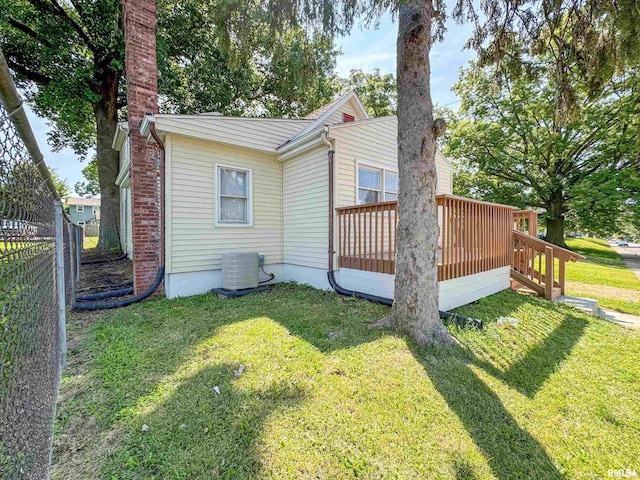 view of side of home featuring a lawn, a chimney, fence, a deck, and central air condition unit