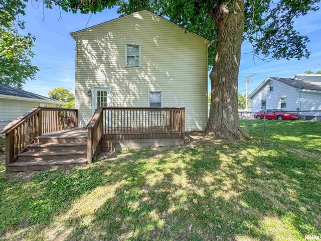 back of property featuring a wooden deck and a lawn