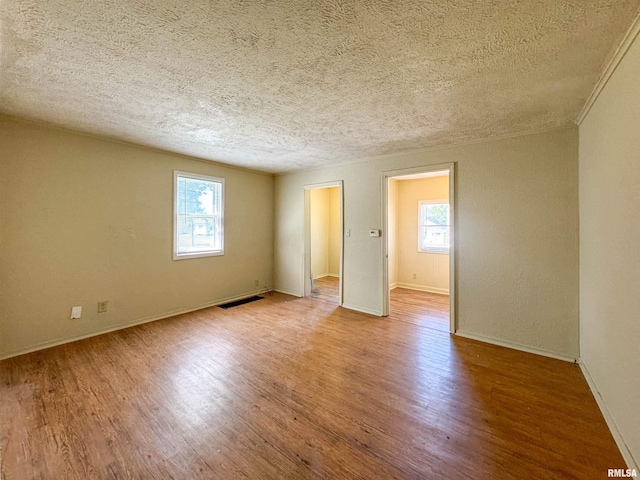 unfurnished room with a textured ceiling, plenty of natural light, and light wood-type flooring