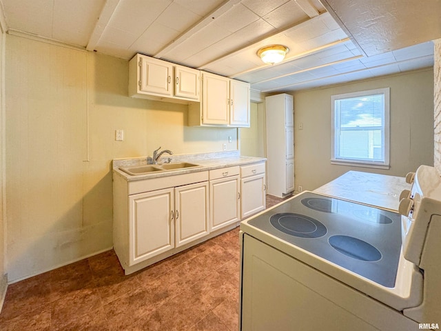 kitchen featuring sink, light tile patterned flooring, white cabinets, and stove