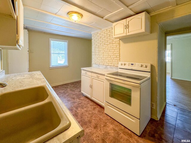 kitchen with tile patterned floors, white cabinets, white electric range oven, and sink