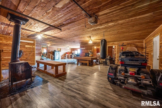 playroom featuring a wood stove, ceiling fan, wood walls, and wood-type flooring