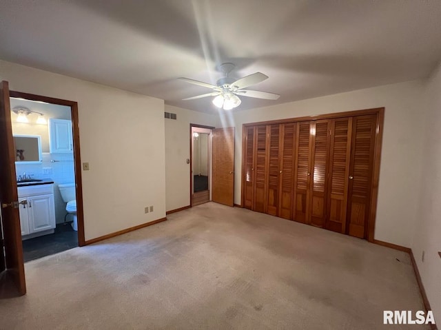849 E Franklin St, Macomb, IL 61455 - unfurnished bedroom featuring a sink, light carpet, baseboards, and ensuite bath