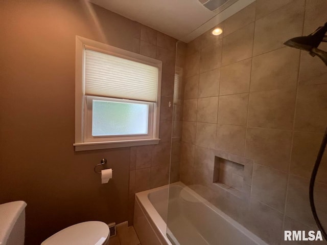 bathroom featuring toilet and tiled shower / bath