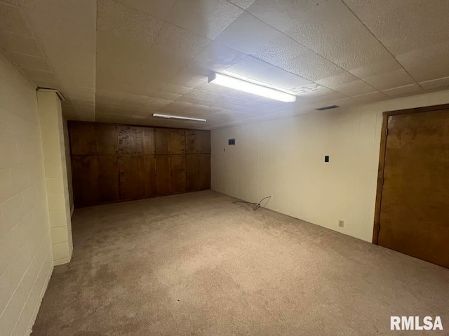 basement featuring wooden walls and light colored carpet