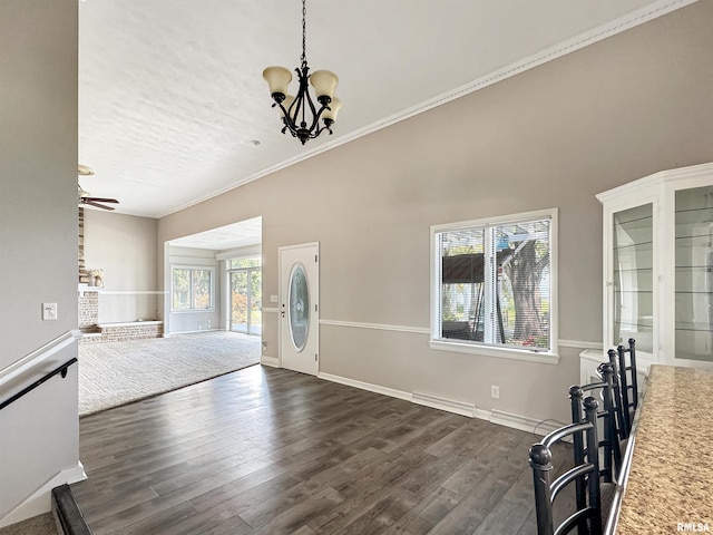 unfurnished living room with crown molding, dark wood-type flooring, a towering ceiling, and ceiling fan with notable chandelier