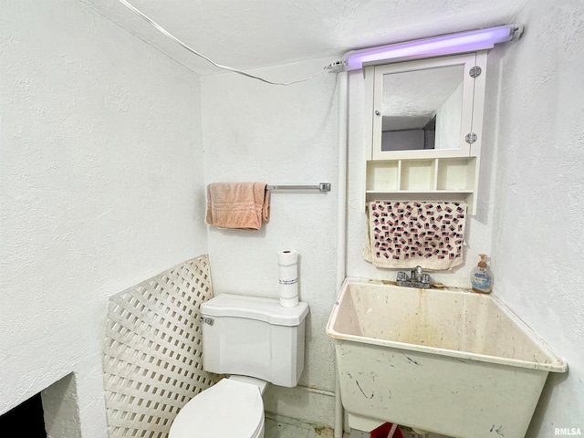 bathroom featuring toilet, sink, and a textured ceiling