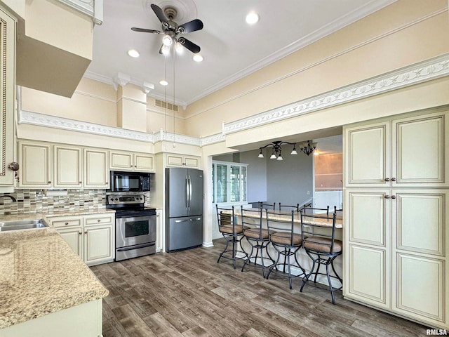 kitchen featuring dark hardwood / wood-style flooring, tasteful backsplash, stainless steel appliances, cream cabinetry, and ceiling fan