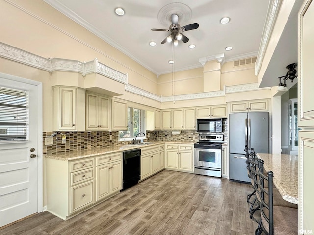 kitchen featuring light stone countertops, black appliances, cream cabinetry, ceiling fan, and decorative backsplash