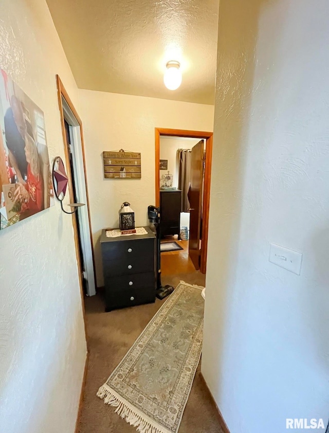 corridor with a textured ceiling and carpet