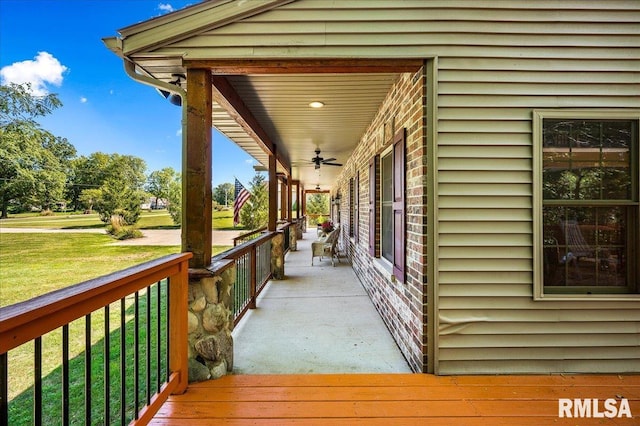 wooden terrace featuring a porch, a lawn, and ceiling fan