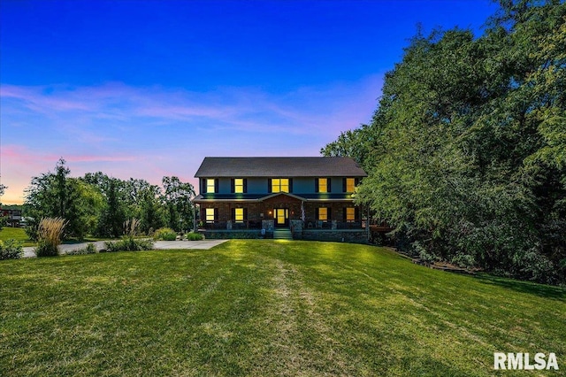 back house at dusk featuring a yard and a porch