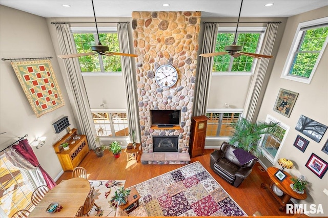 living room featuring hardwood / wood-style floors, ceiling fan, a fireplace, and a healthy amount of sunlight