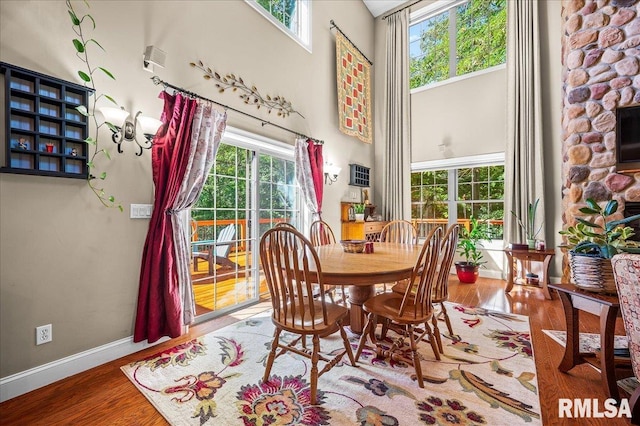 dining room with a high ceiling, wood-type flooring, and a fireplace