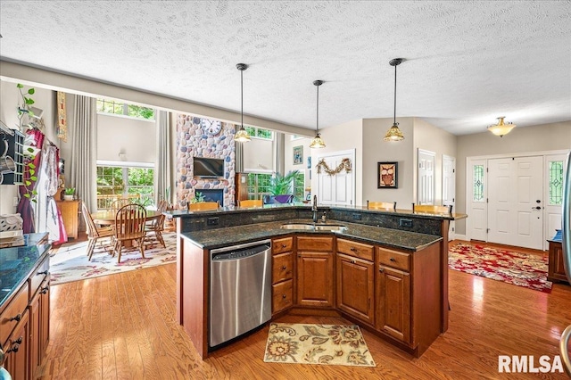 kitchen with light hardwood / wood-style flooring, dark stone countertops, sink, and stainless steel dishwasher