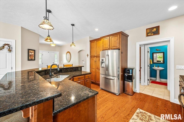 kitchen featuring a center island with sink, sink, stainless steel fridge, and light hardwood / wood-style floors