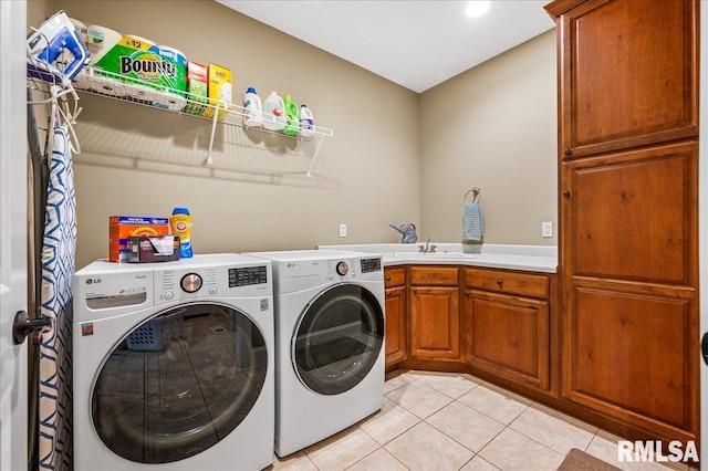 laundry area featuring cabinets, light tile patterned floors, and washer and clothes dryer