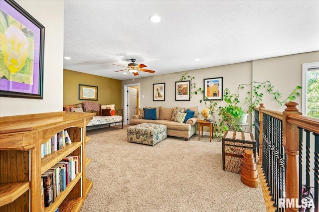 carpeted living room featuring ceiling fan and a textured ceiling