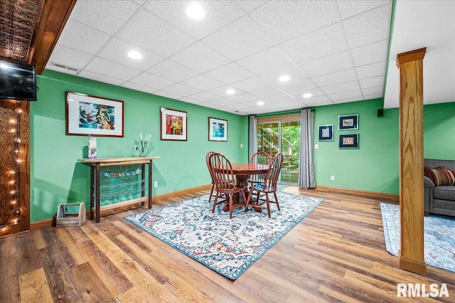 dining room featuring hardwood / wood-style floors and a drop ceiling