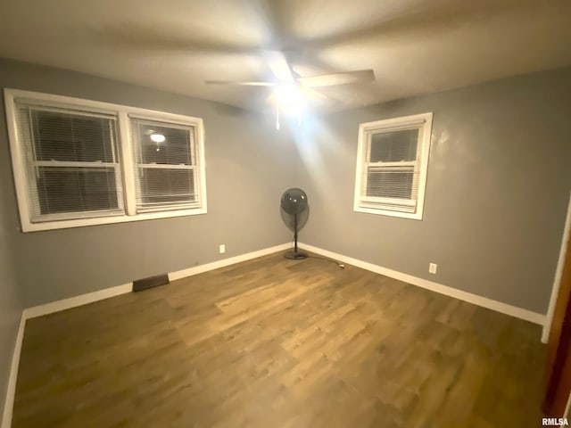 empty room featuring dark wood finished floors, baseboards, and ceiling fan