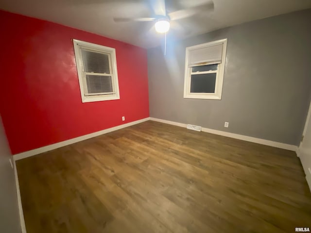 empty room with a ceiling fan, baseboards, visible vents, and wood finished floors