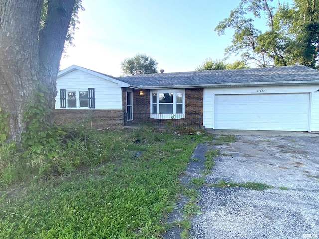 ranch-style home featuring aphalt driveway, brick siding, an attached garage, and roof with shingles